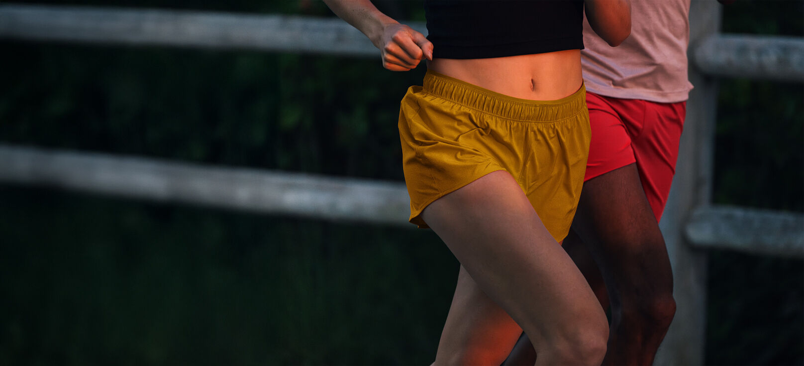 Two individuals running outside, wearing New Balance RC shorts.