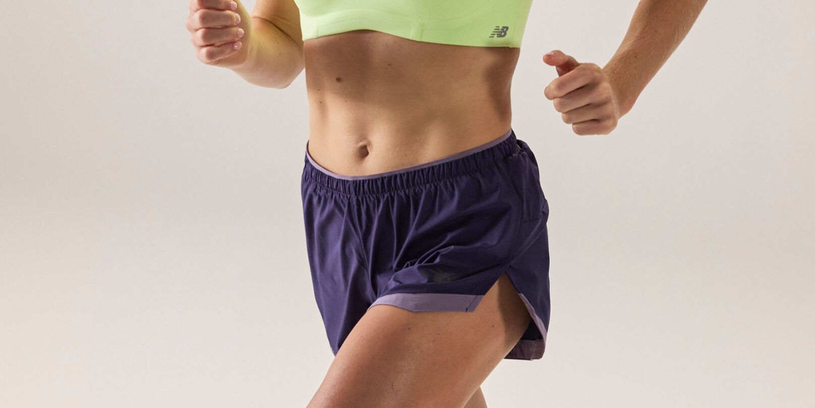 Two individuals running outside, wearing New Balance RC shorts.