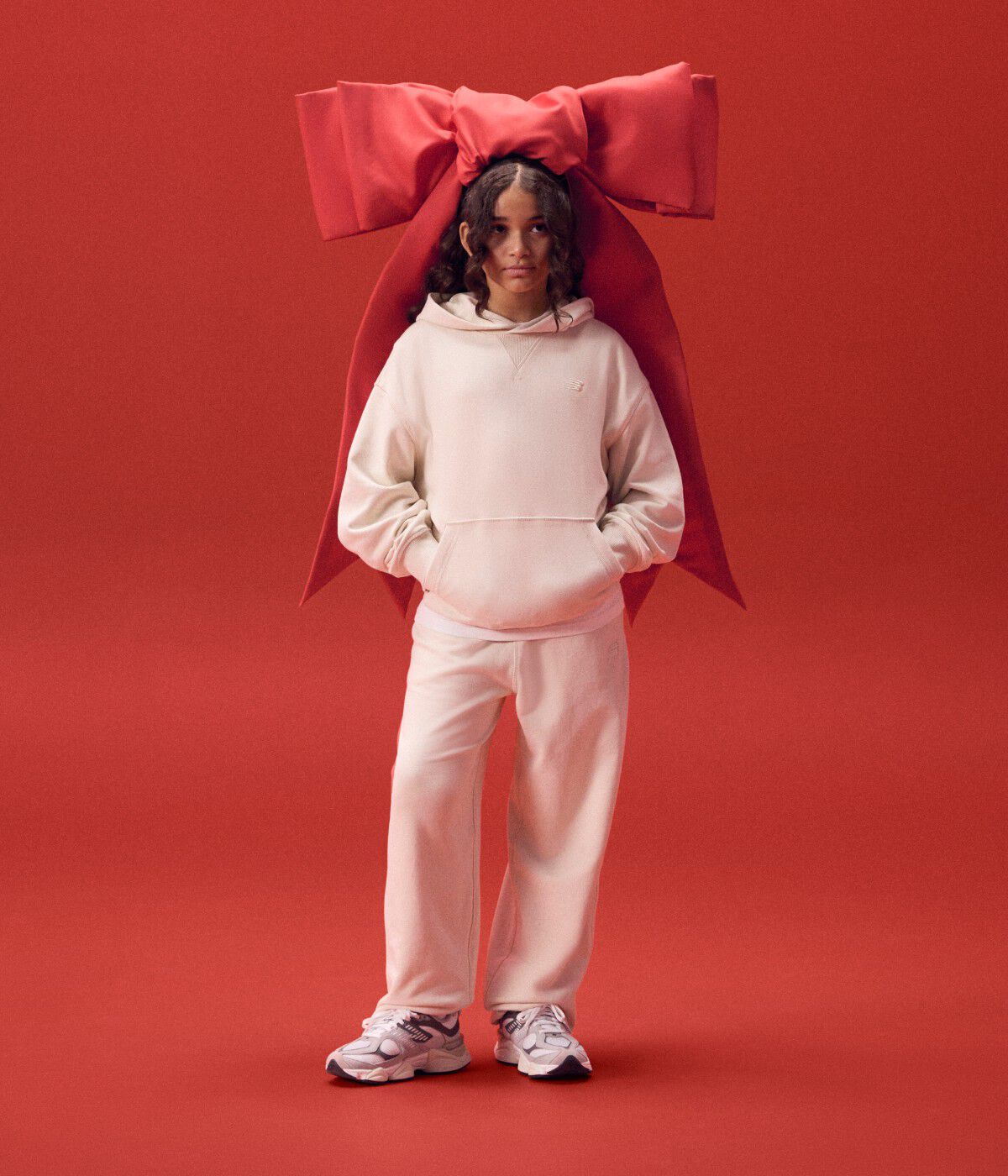 Female wearing a white matching set with a red ribbon on her head.