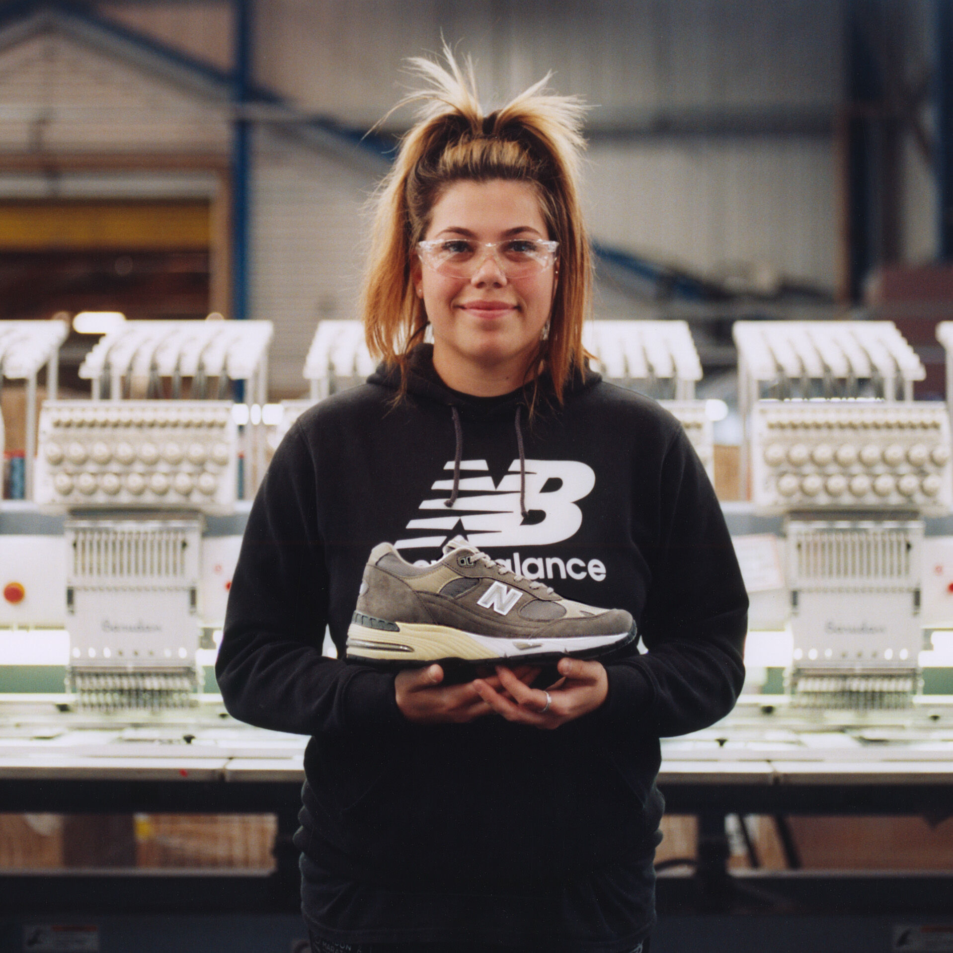 Woman holding MADE footwear against factory background