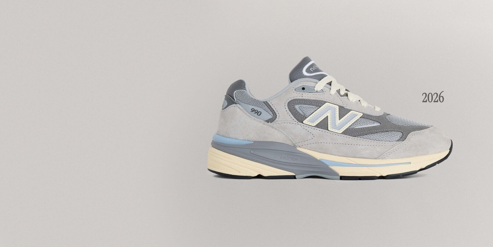 A grey 990v7 sneaker sitting on a grey background.